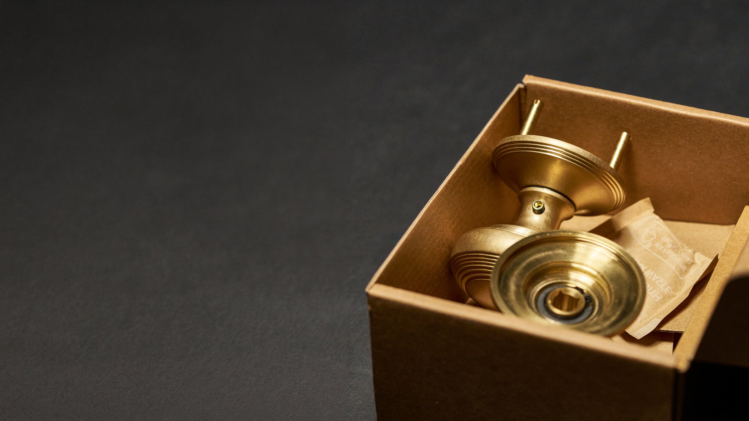 Brass door handle in a cardboard box on a dark background