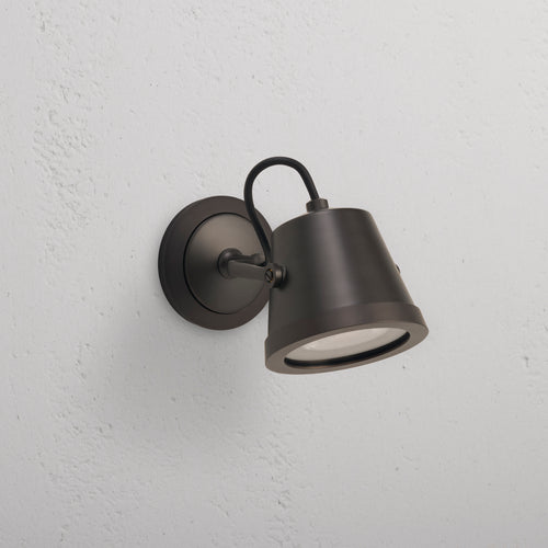 Bronze Cambridge Wall Floodlight, an outdoor fixture with round base and angled cone shade on white wall.