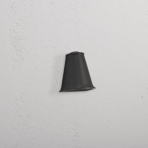 Southwark Mast Light – Bronze, a small bronze wall light with a rounded design, mounted on a white textured wall.
